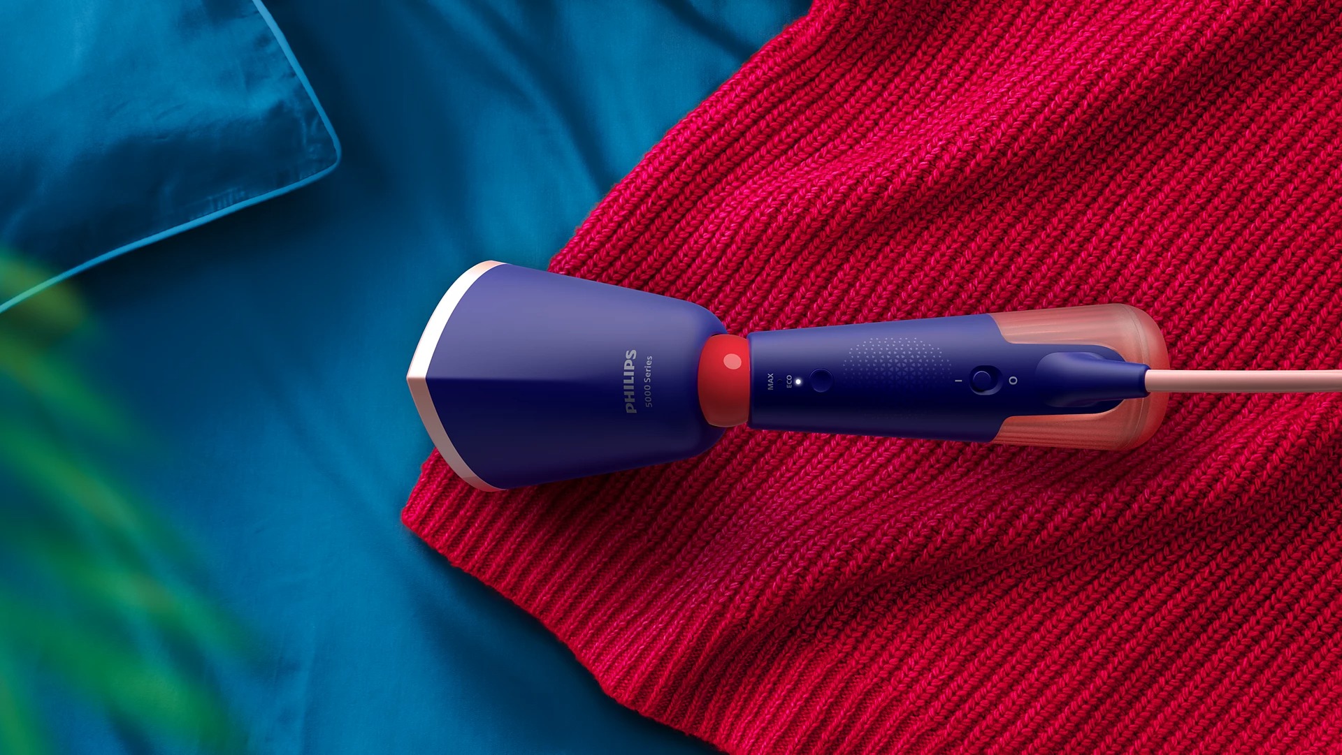 Philips 5000 Series STH5030/20 handheld steamer u radu na crvenom pletenom puloveru