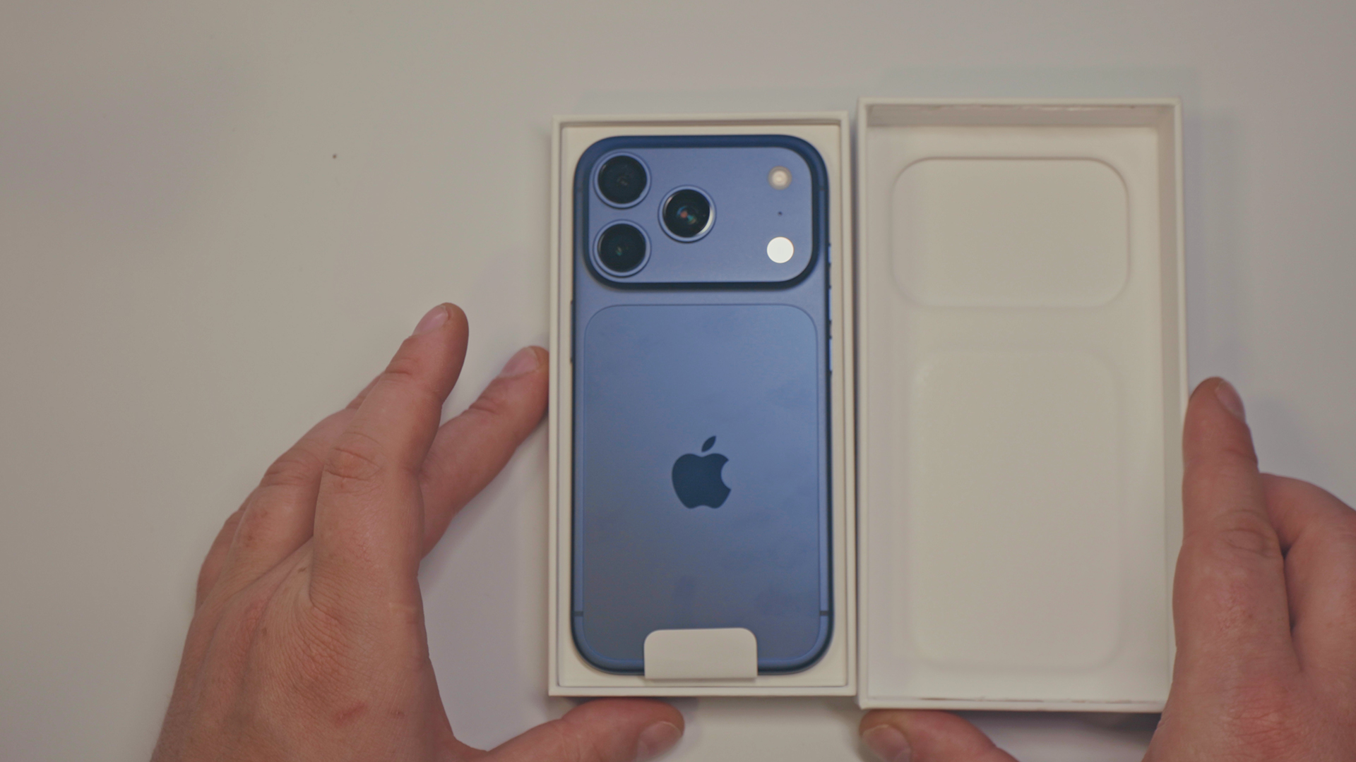 Fotografija iz ptičje perspektive novog iPhone 17 pro pametnog telefona na bijeloj pozadini i otvorenoj kutiji gdje se vidi unboxing uređaja i sve što se dobiva u paketu. 