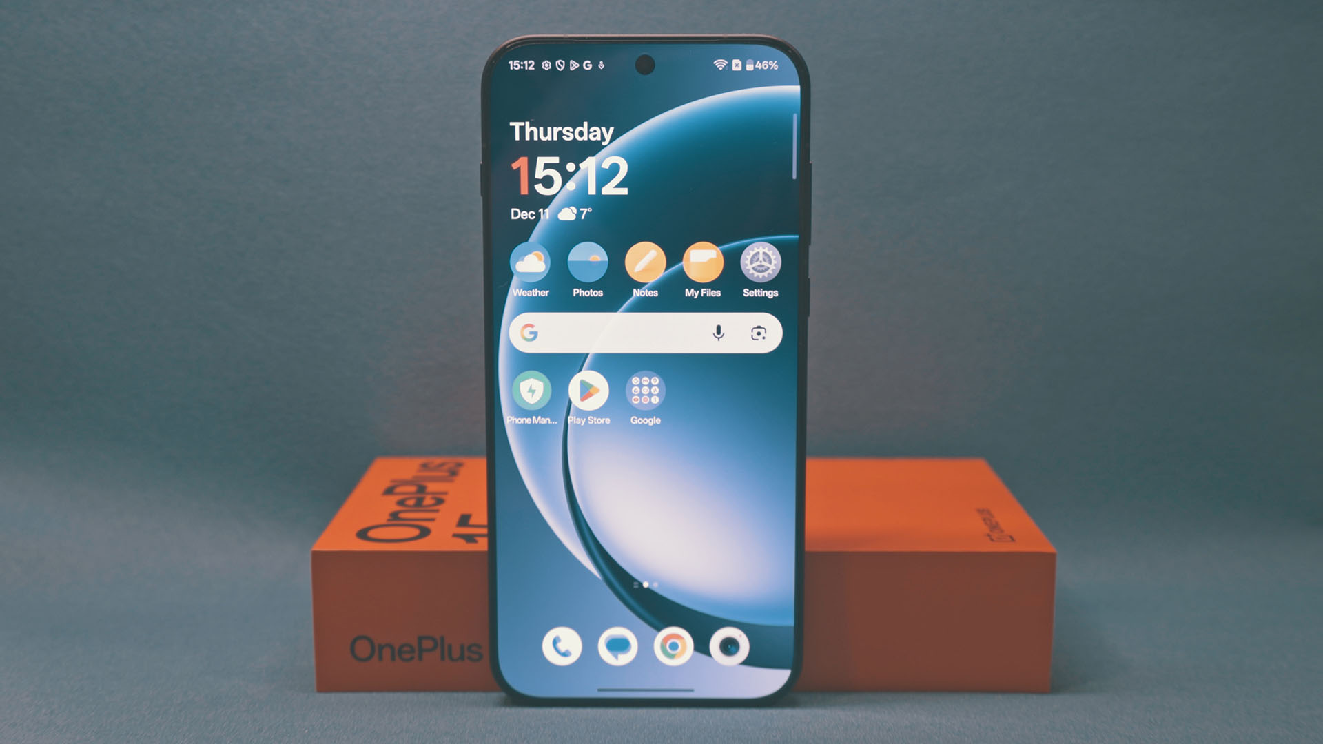 OnePlus 15 u uspravnom položaju koji prikazuje upaljeni ekran s crvenom kutijom koja ga drži