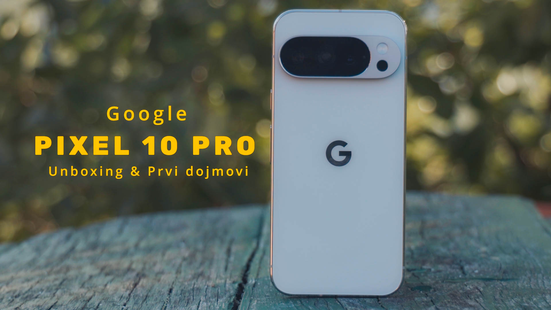 Pametni telefon Google pixel 10 pro stoji uspravno na drvenom stolu u pozadini je zeleno bilje i drvo