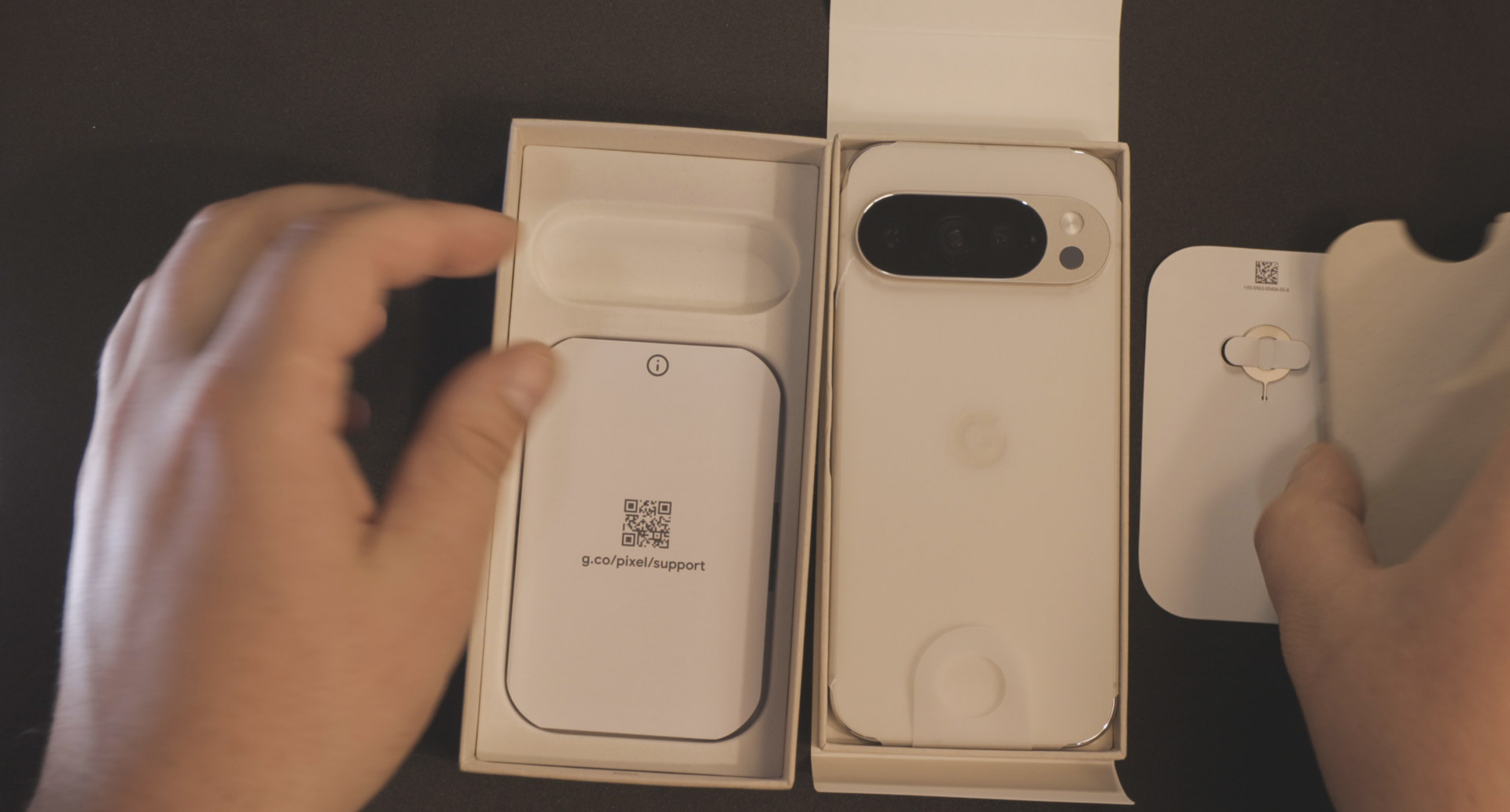Sadržaj kutije Google Pixel 10 pro pametnog telefona u porculan boji na crnoj pozadini
