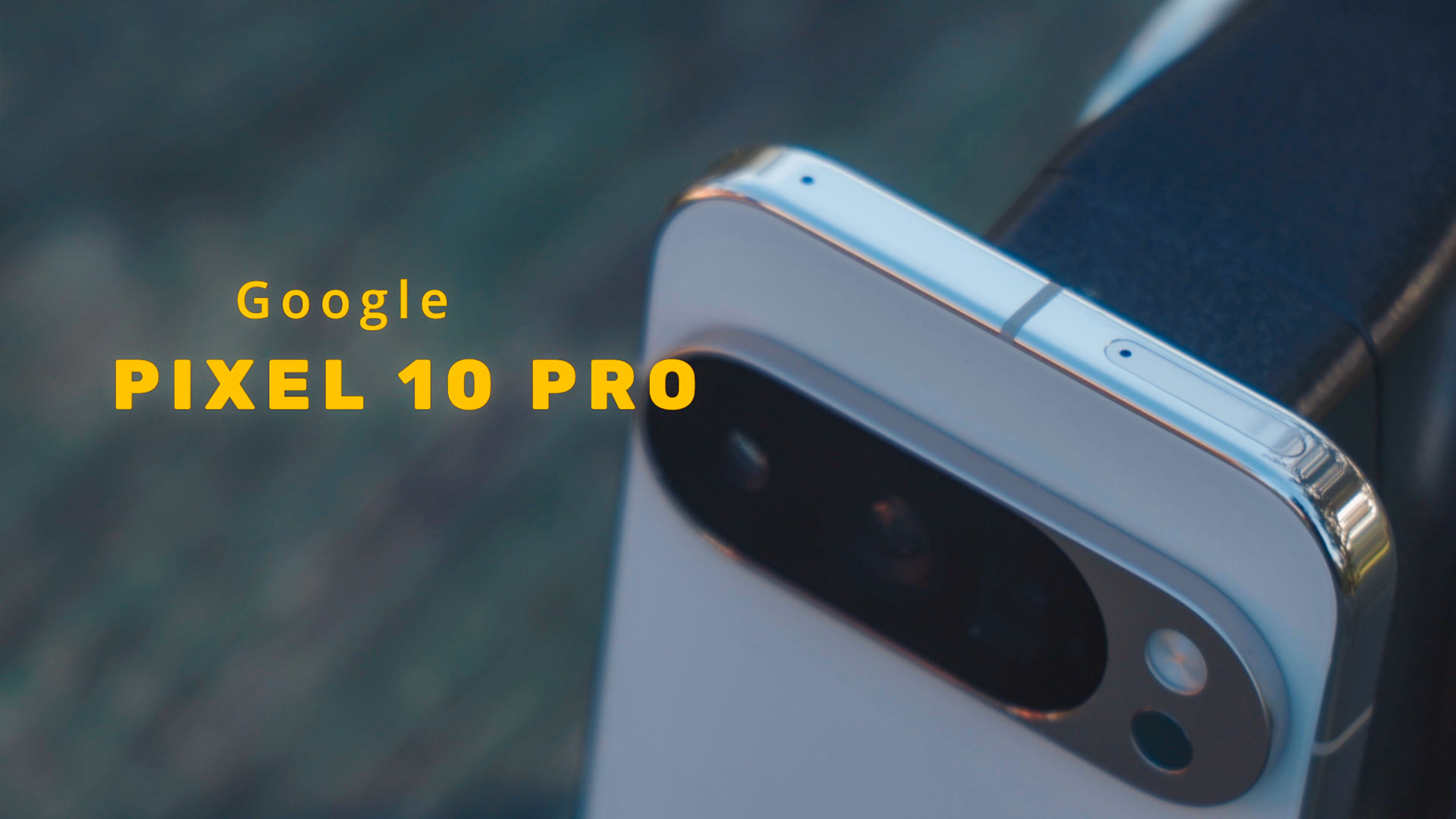 Zumirani pogled na presjek kamera i aluminijski okvir koji ima Google Pixel 10 telefon na zelenoj drvenoj pozadini.