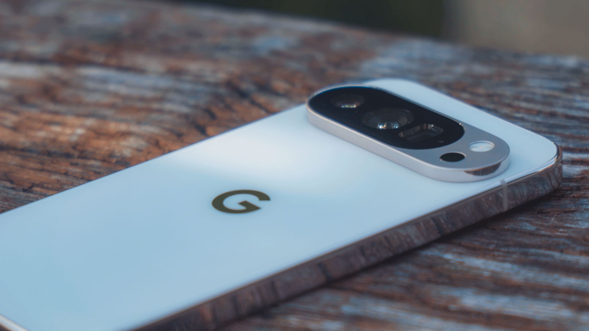 Pogled na poleđinu pametnog telefona koji se nalazi na drvenoj pozadini kako bi se zumirano vidio sustav kamera na novom Google Pixel 10 telefonu